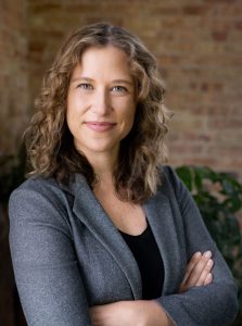 Lauren Hasselbacher, smiling woman with brown hair in a grey blazer.