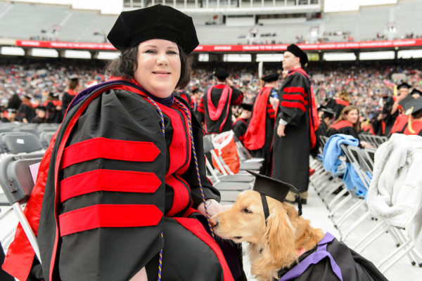 student and her service dog at commencement ceremony in cap and gown