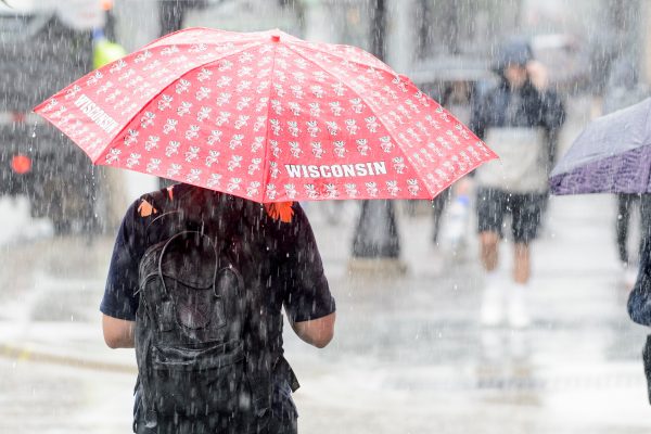 two students walk in the rain with umbrellas