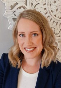Jenna Konruff, Smiling woman with wavy blond shoulder-length hair, wearing a navy blazer and a white shirt.