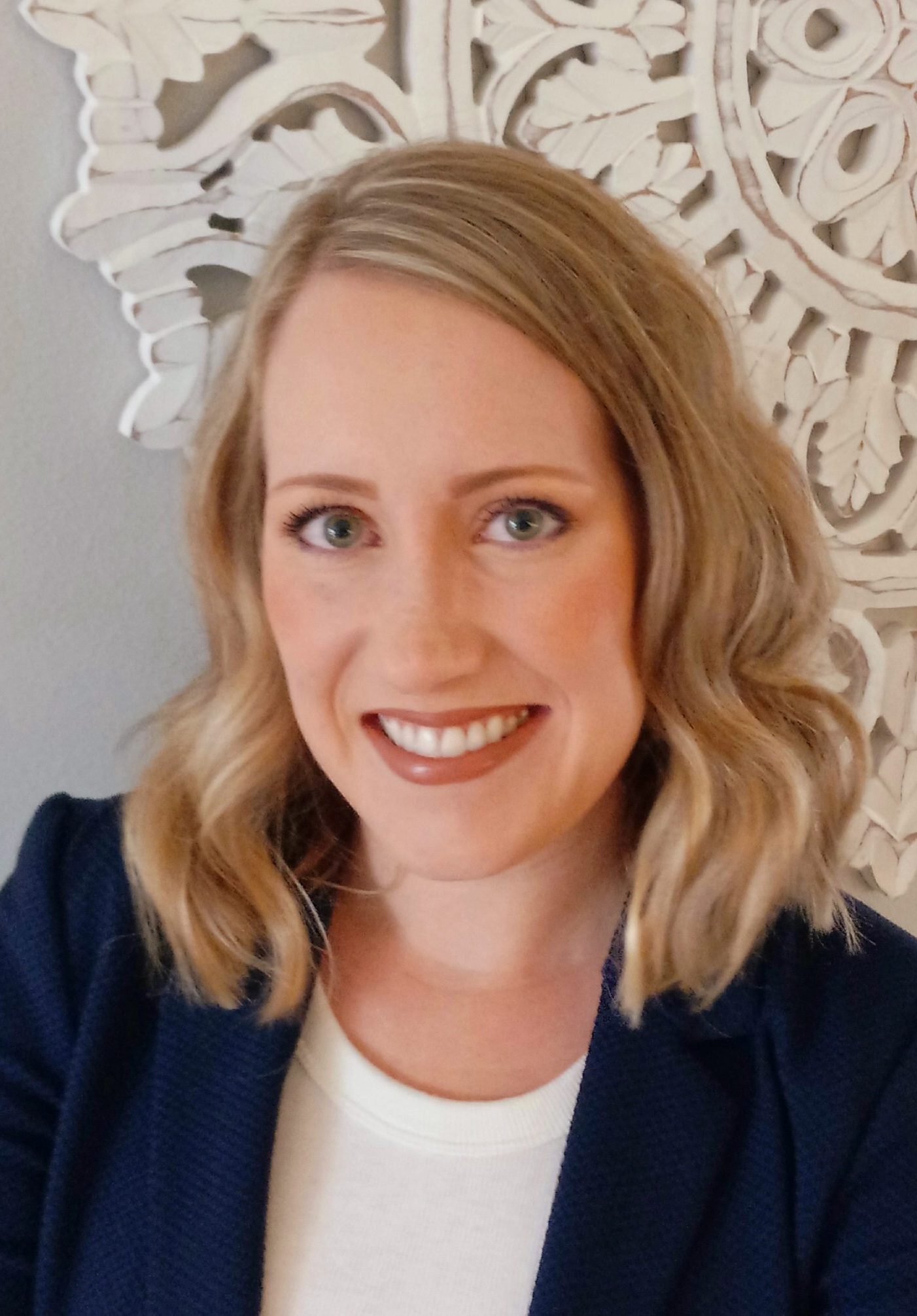Jenna Konruff, Smiling woman with wavy blond shoulder-length hair, wearing a navy blazer and a white shirt.