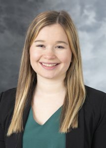 Jenna Schwab, Smiling woman with sandy blonde hair, wearing a teal colored shirt and a black blazer.